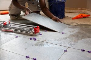 Services one man installing tile in a kitchen remodel.