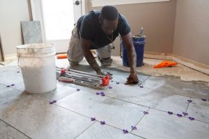 Services one man installing tile in a kitchen remodel.